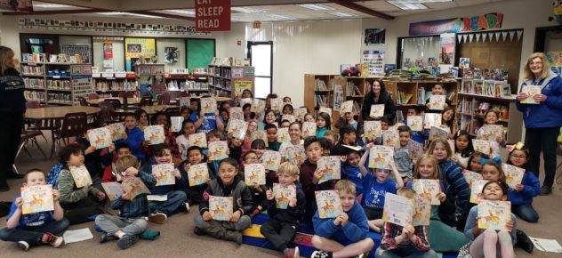 Approximately 30 smiling and happy school children holding up their copies of "Bee A Dreamer."